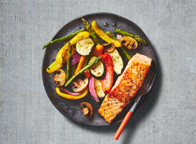 A picture of seafood served on a black plate with veggies